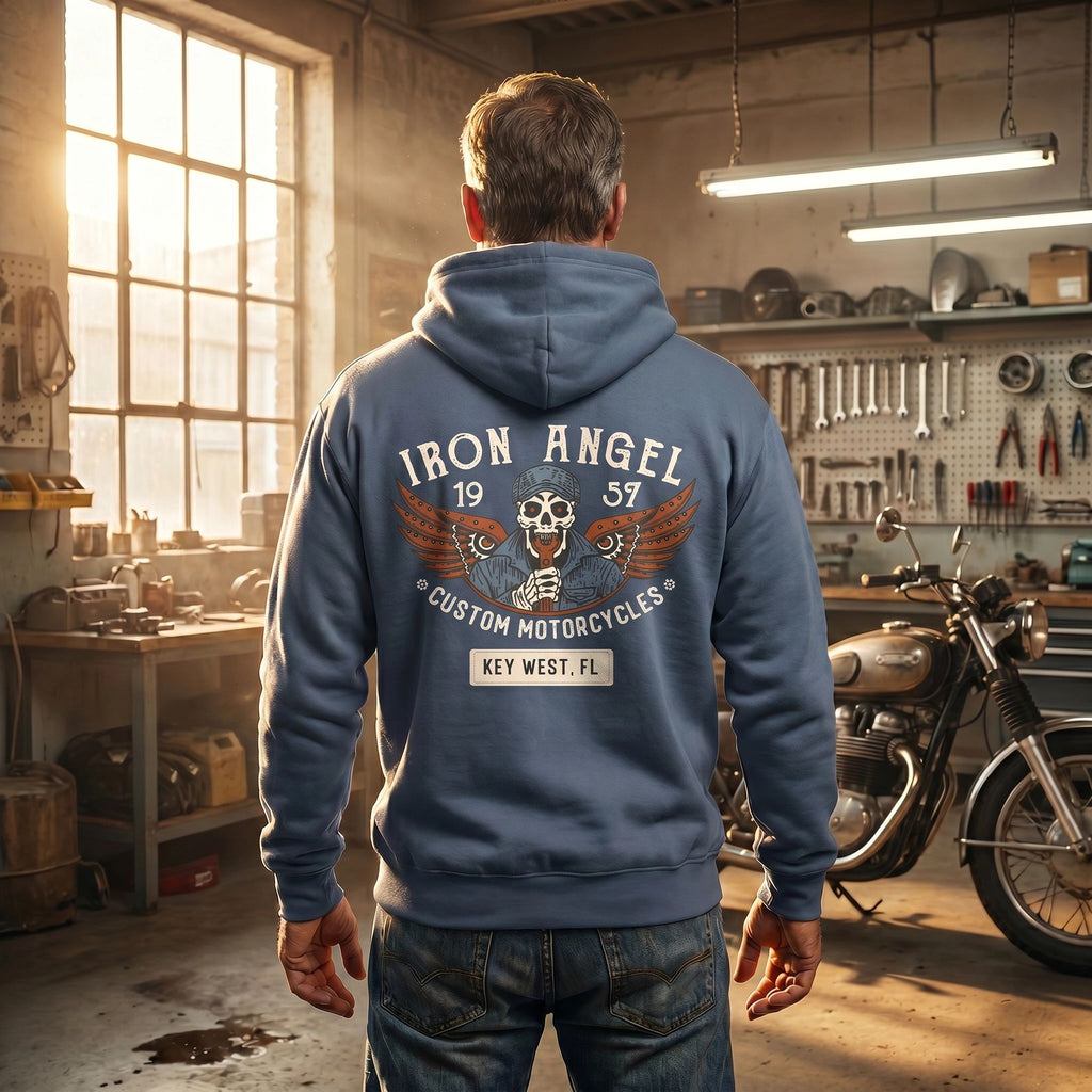 Streetwear model lifestyle back view wearing the Iron Angel Custom Motorcycles Comfort Colors 1567 heavyweight 9.5 oz fleece pullover hoodie in Denim Blue with skeleton wrench-bearer with mechanical wings built from gears and chain, and 1957 Key West custom garage crest.
